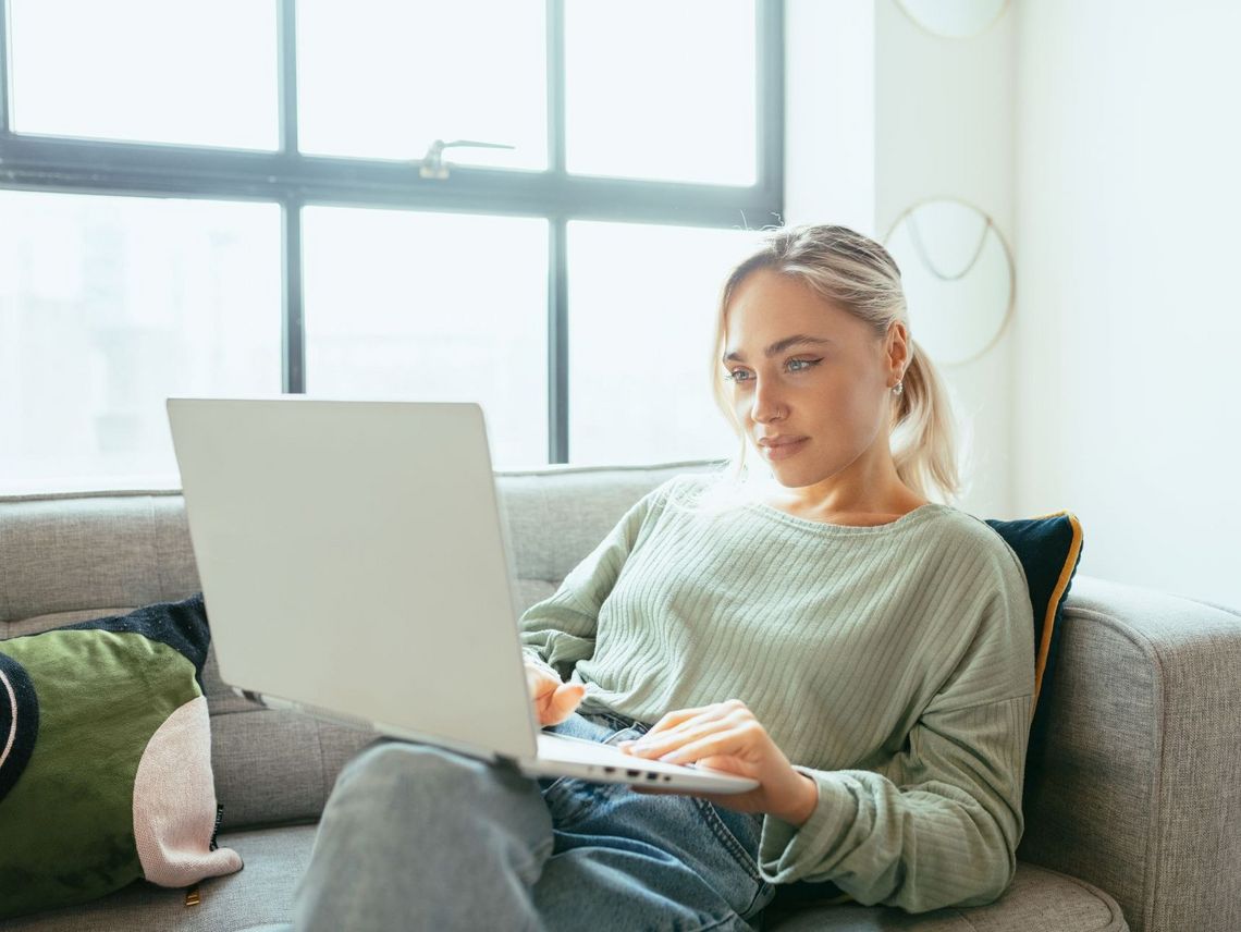 Junge Frau auf dem Sofa sitzend am Laptop