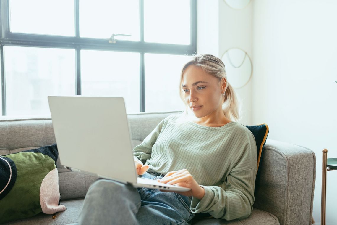 Junge Frau auf dem Sofa sitzend am Laptop