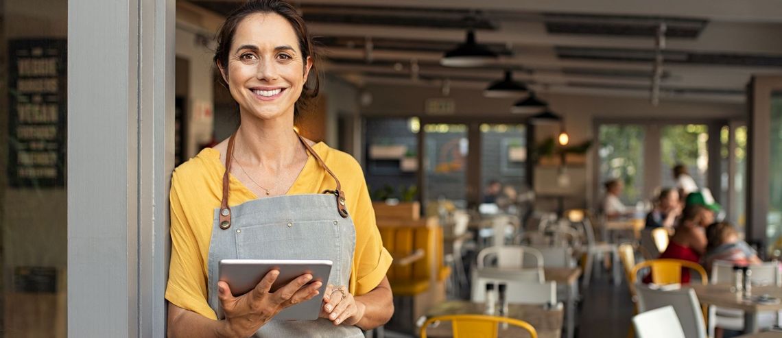 Frau mit Laptop stehend vor einem Cafè