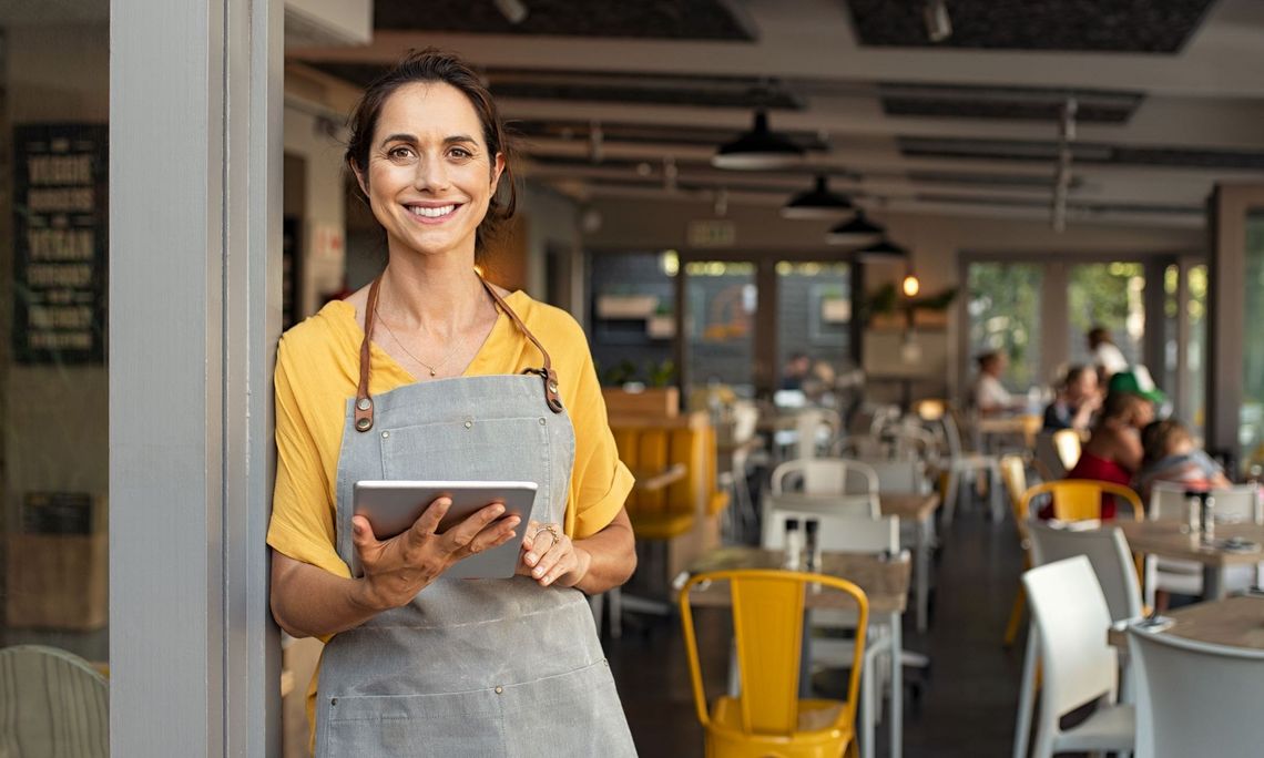 Frau mit Laptop stehend vor einem Cafè