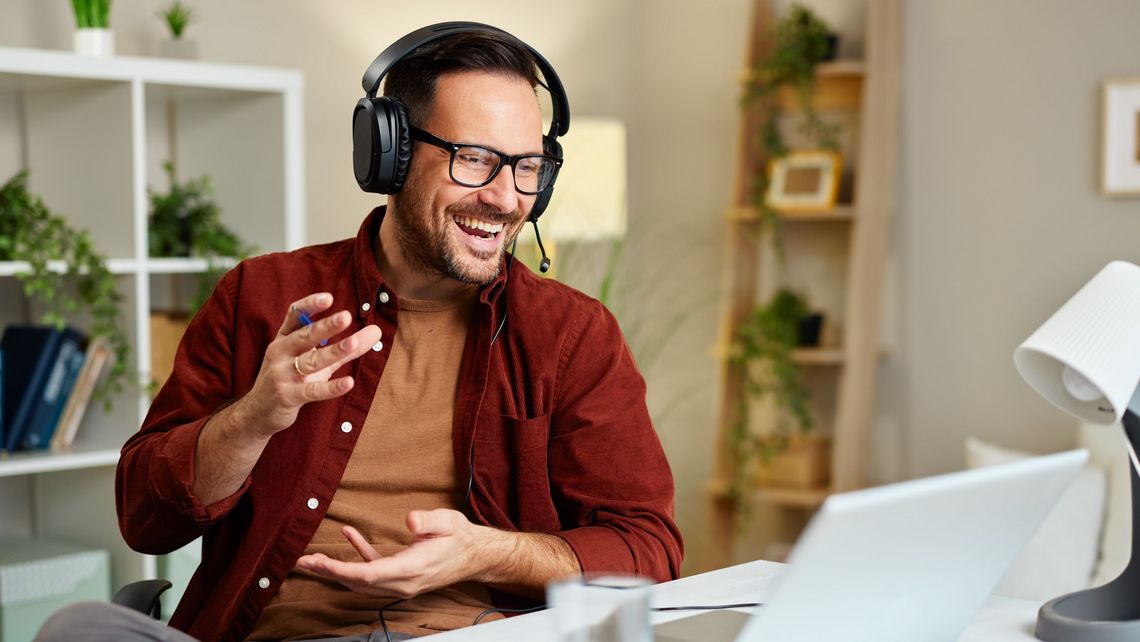 Mann am Telefon vor dem Laptop sitzend im Büro