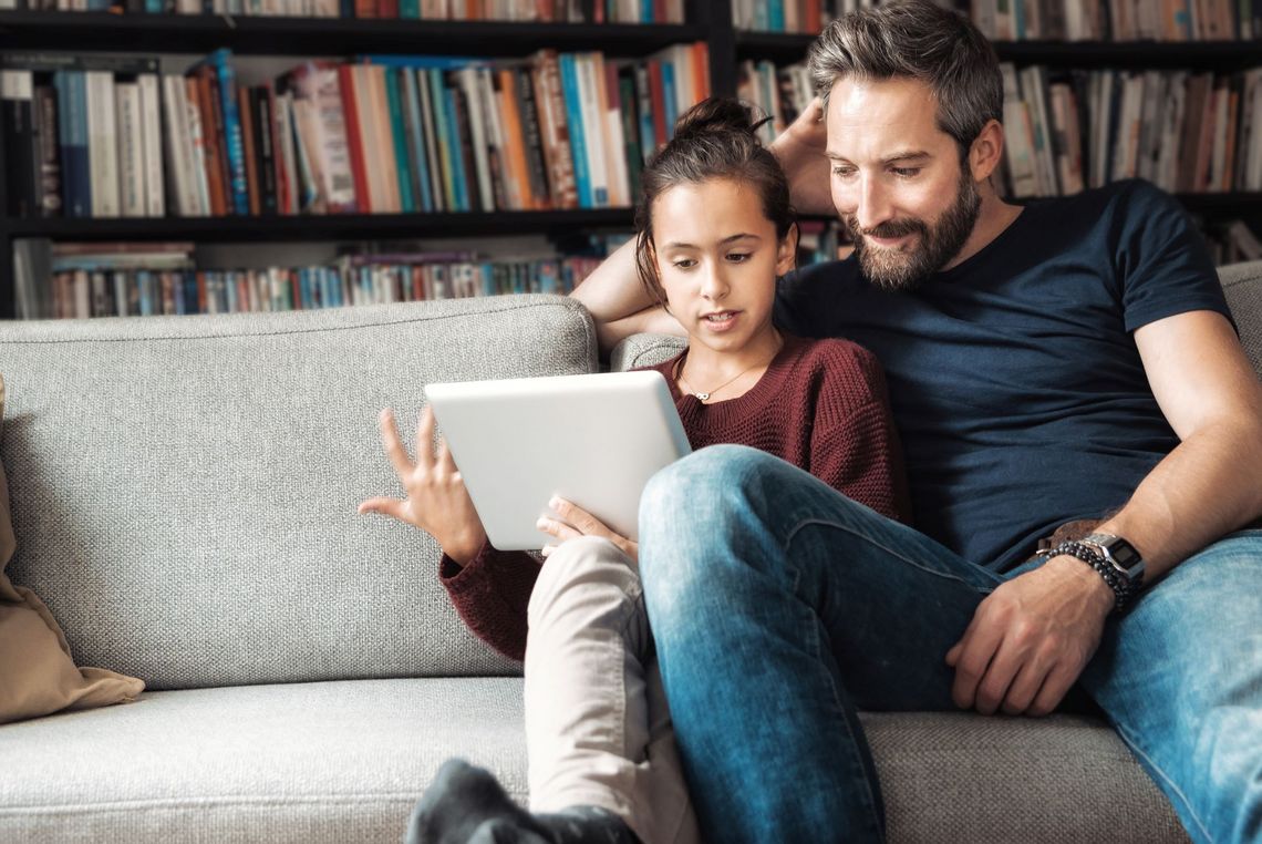 Vater mit Tochter auf dem Sofa sitzend am Laptop