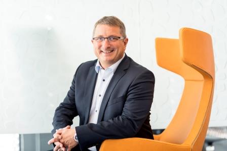 Jochen Schmid in einem orangenem Stuhl sitzend 